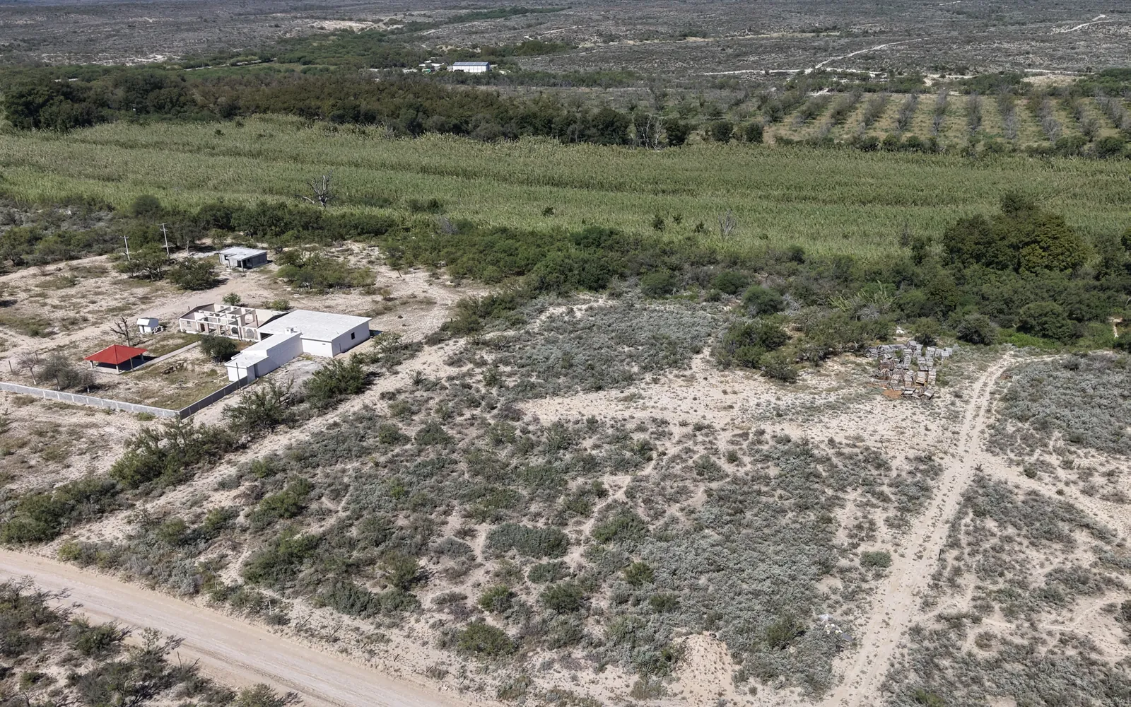 Vista aérea del Terreno Río Escondido en Piedras Negras, con el camino de terracería y la franja verde a lo largo del río